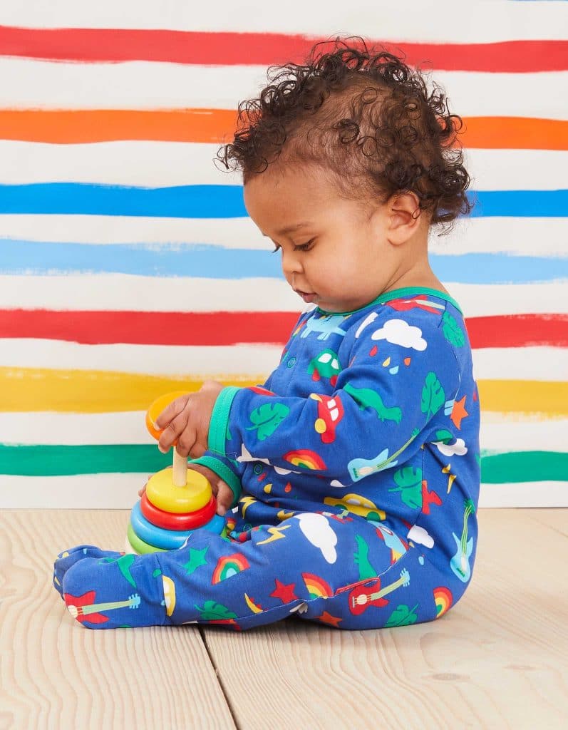 A baby wearing one of Toby Tiger's bright ethical babygrows.