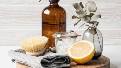 Amber glass bottle next to lemon, scrubbing brush and cloth.