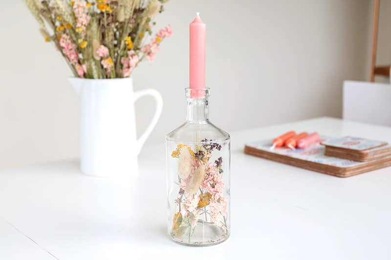 Gin bottle upcycled into candle holder with dried flowers inside it.