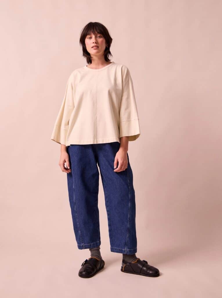 A dark haired person wearing beyond nine denim trousers