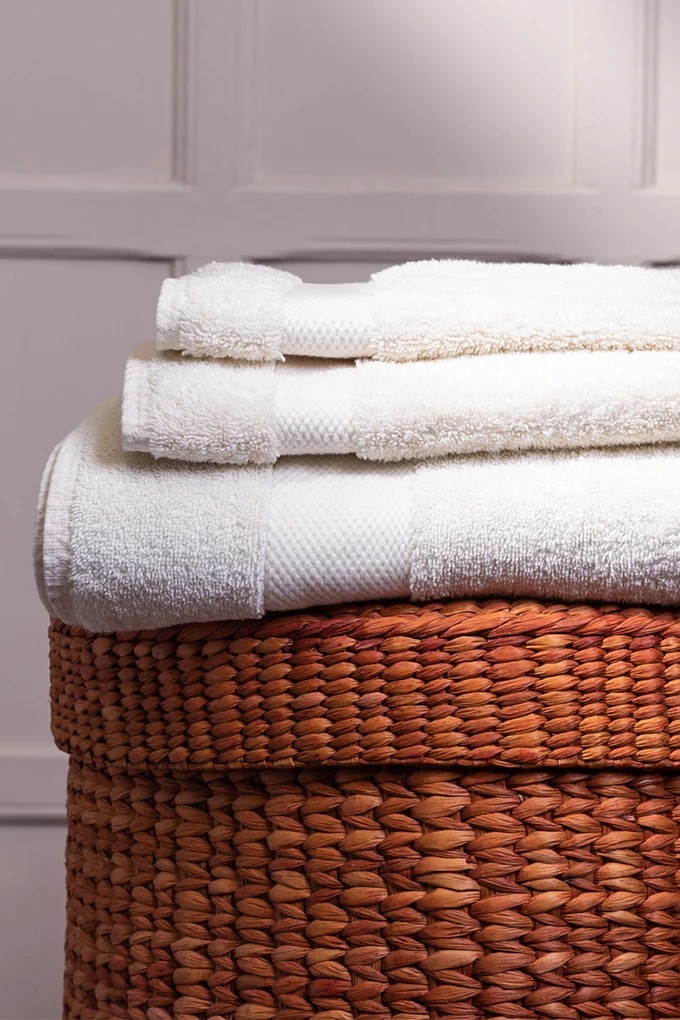 Pile of white organic towels folded on top of a wicker basket