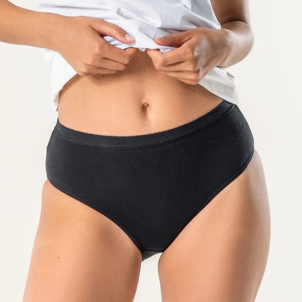 Person in a white t-shirt wearing plain black undies from Natural Collection Select.