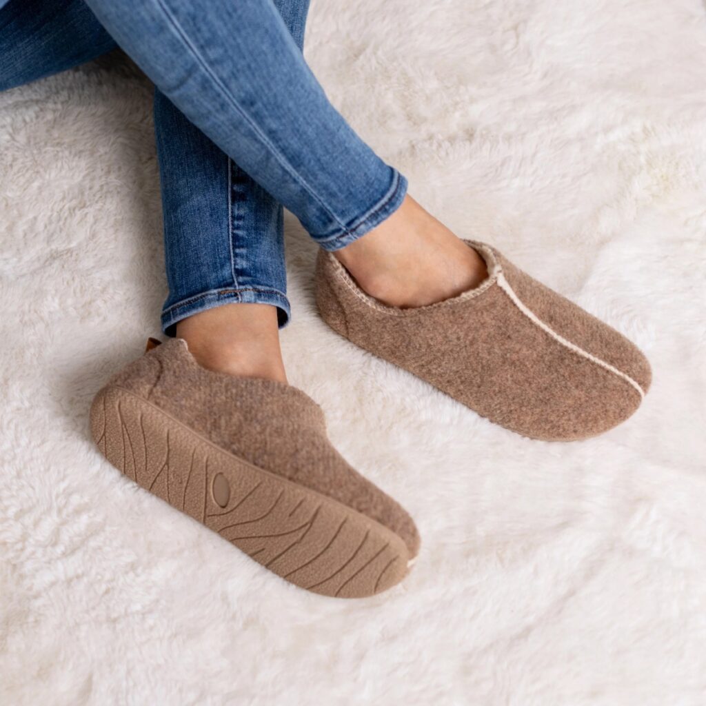 Person wearing brown recycled polyester slippers from SnugToes