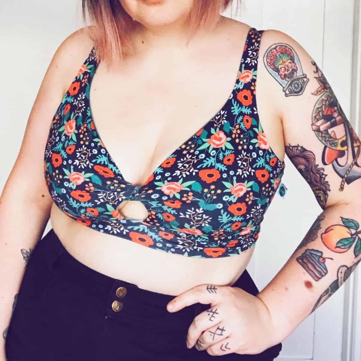 Person with tattoos wearing a navy organic cotton floral bra from plus-size sustainable brand Sprout Organic.