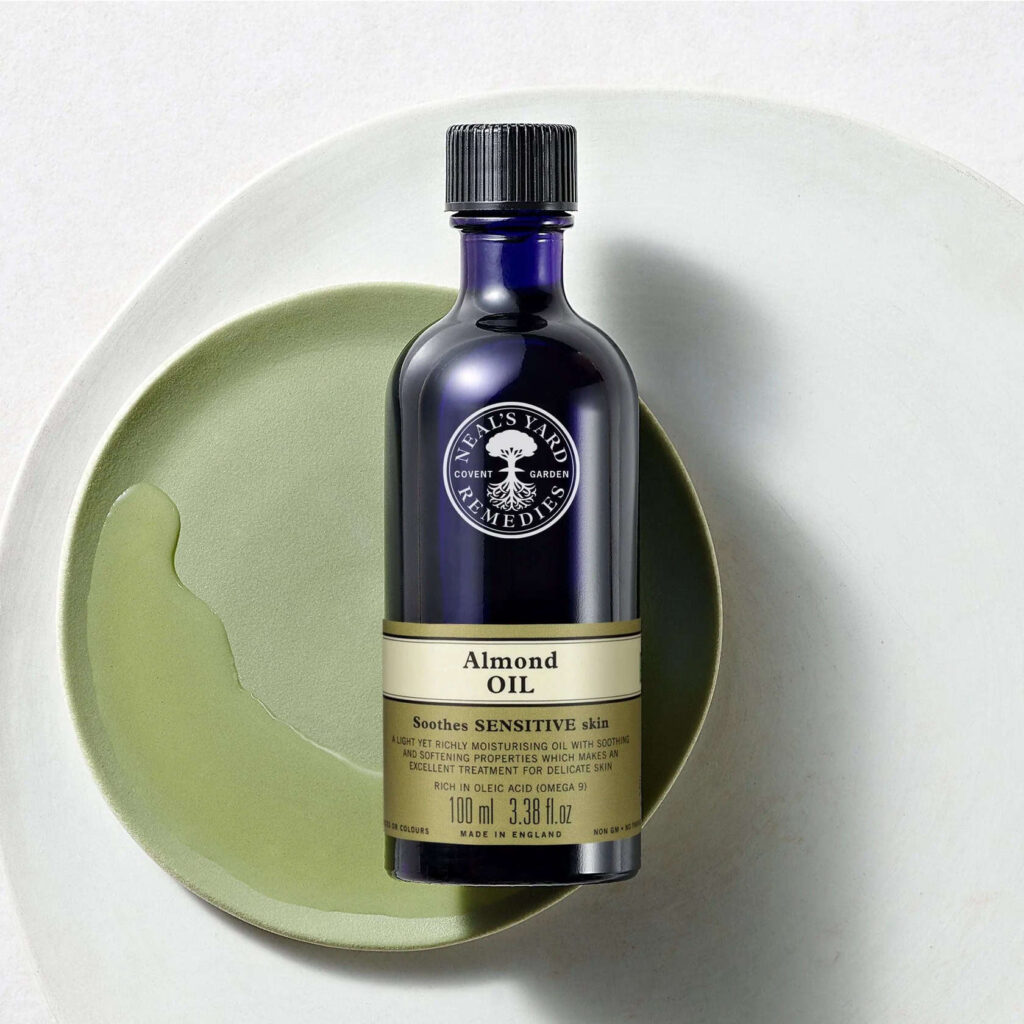 Blue bottle of almond oil from Neal's Yard, lying on a green plate.